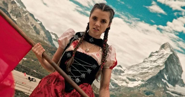 Mad Heidi mit Fahne vor einem Bergpanorama