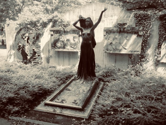 Bronze-Statue auf dem Alter Johannisfriedhof Leipzig vor Reliefwand