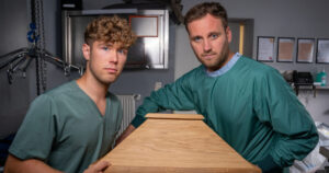 Zwei Männer stehen neben einem Sarg