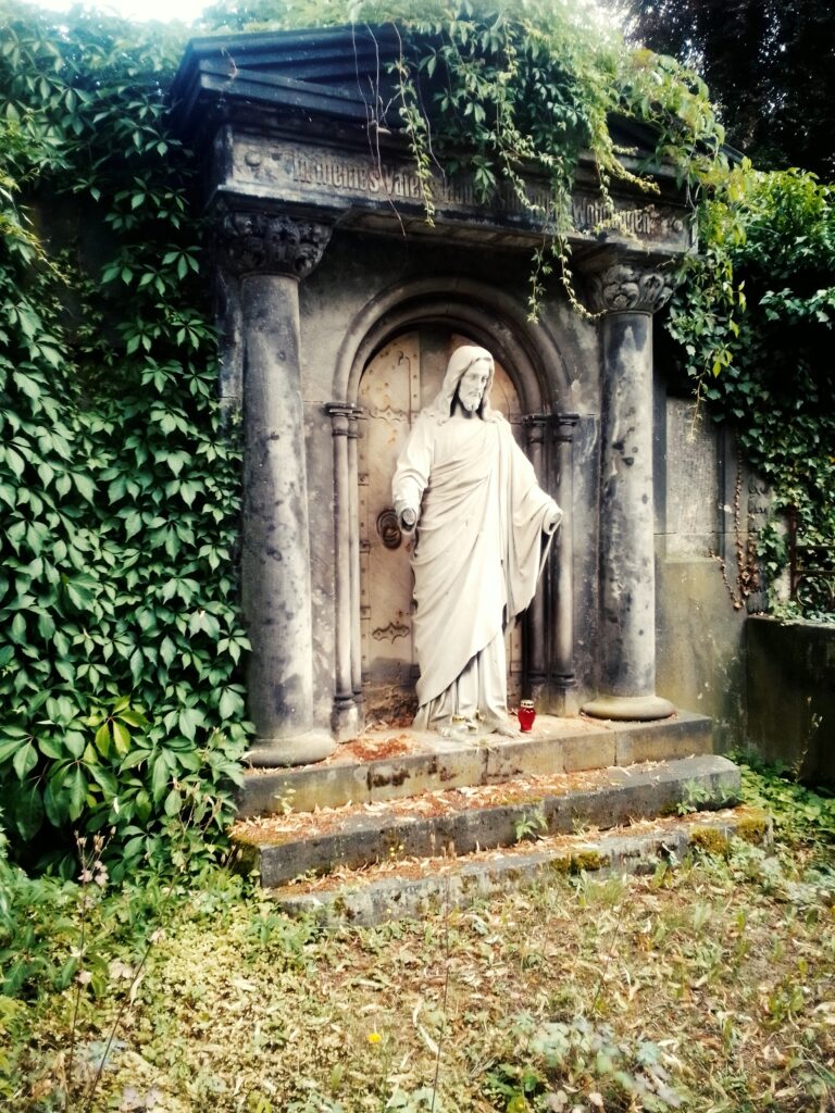 Verhüllte Figur klopft an Tür eines Mausoleums, Friedhof Meissen