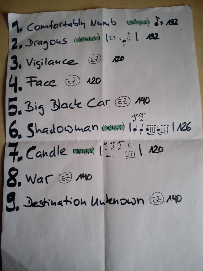 Handschriftliche Liste mit Titeln von Musikstücken und deren Dauer auf einem Blatt Papier.