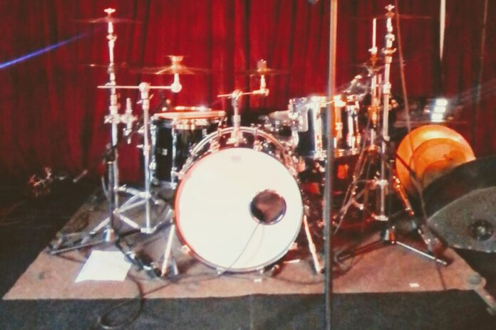 Schlagzeugset mit Bassdrum, Snare, Tom-Toms und Becken auf einer Bühne.
