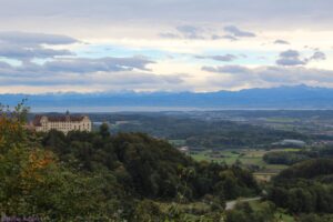 Aussicht vom Bellevueplatz in Heiligenberg auf Schloss Heiligenberg, den Bodensee und die schneebedeckten Alpen.