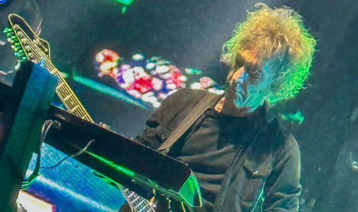 Perry Bamonte steht auf der Bühne mit eine Gitarre