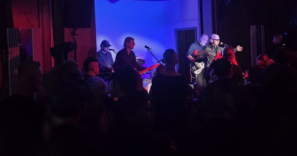 Band spielt live Musik auf einer Bühne mit blauem und rotem Licht