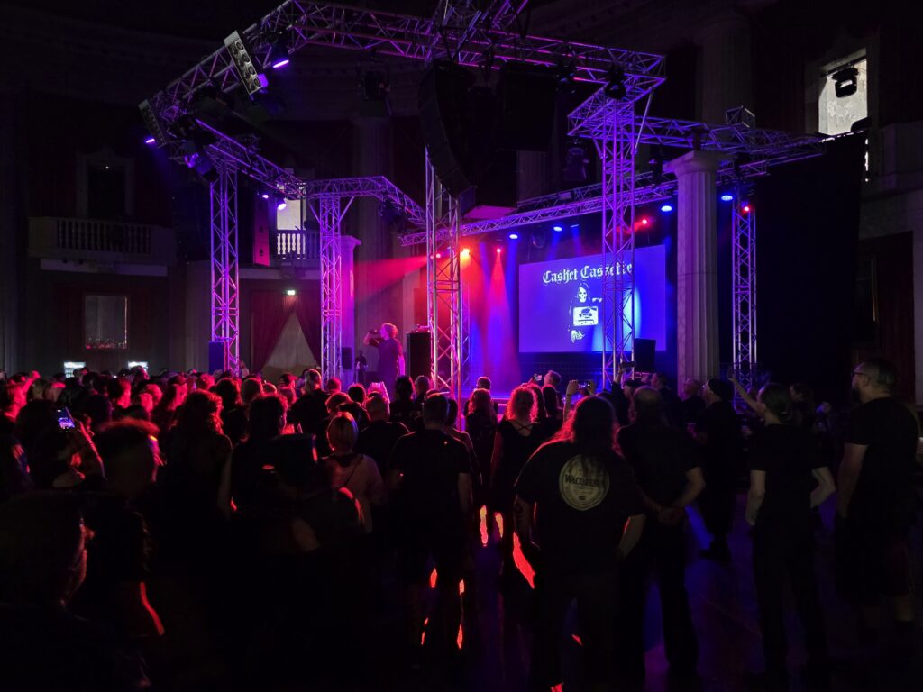 Besucher bei einem Konzert mit Bühnenbeleuchtung und Band auf der Bühne